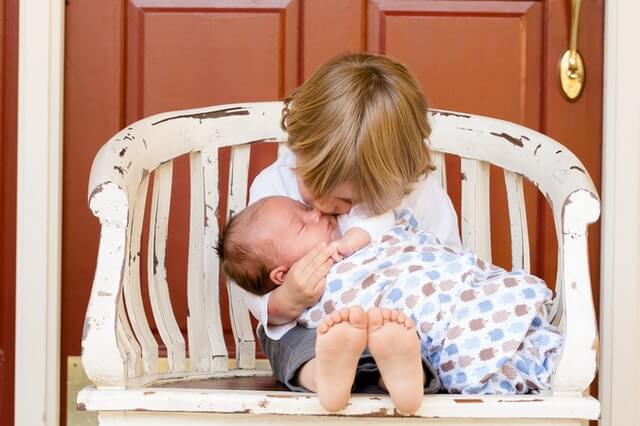 A boy kisses his beautiful new born brother