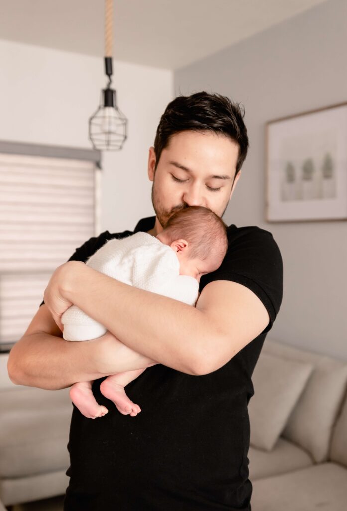 father carries his newborn baby